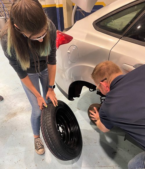 A young woman and a mechanic change a tire
